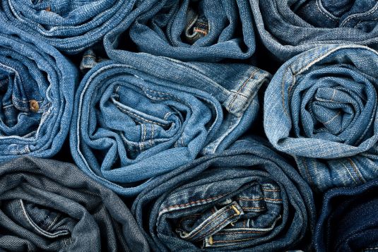 mehrere Jeans liegen gerollt übereinander
